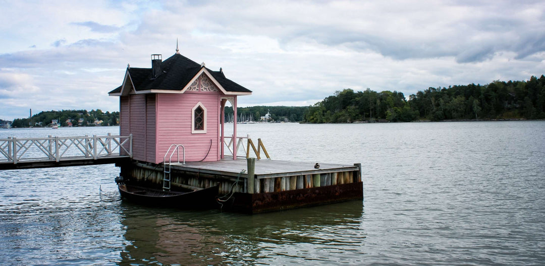 Vaaleanpunainen pihasauna veden äärellä